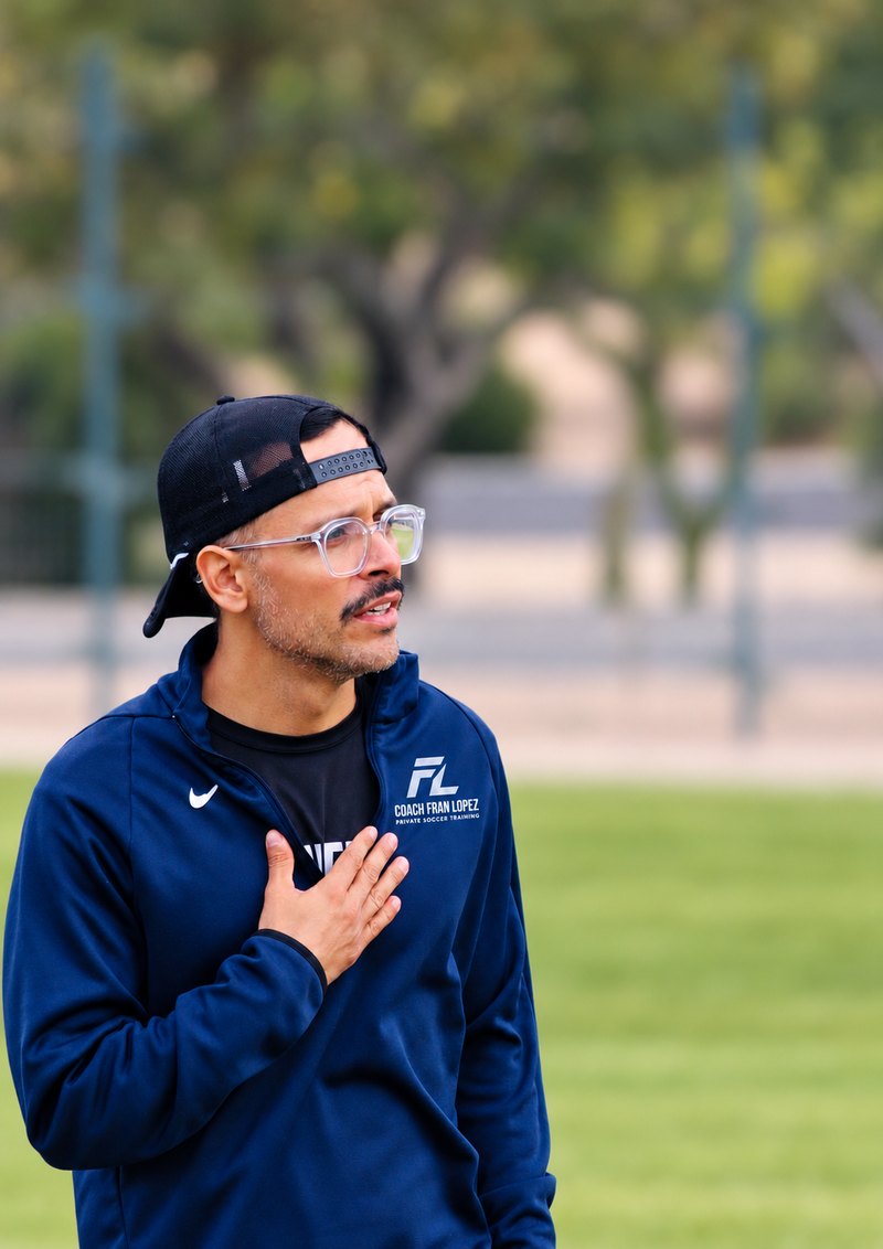 Coach Fran Lopez on the soccer field with his hand on his chest